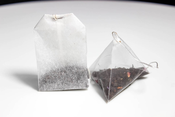 Two tea bags of different shapes on a white background. Selective shot. - Photo, Image