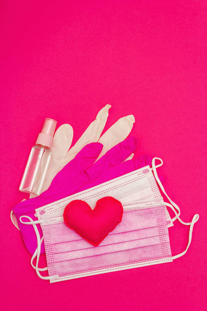 Red heart with medical protection masks and gloves on bright pink background, copy space. Concept of healthcare, self-defense - Photo, Image