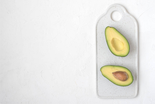 Sliced avocado on a white cutting board. Top view, for menu. Copy space. - Fotó, kép