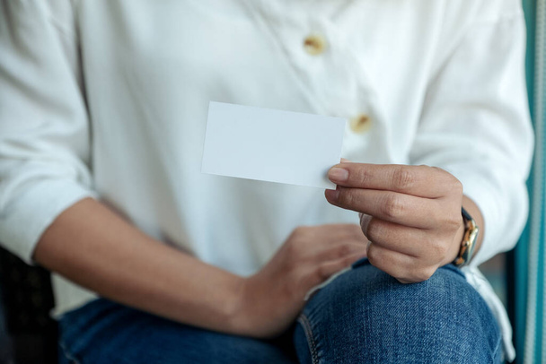 A woman holding and showing a blank empty business card to someone  - Photo, Image