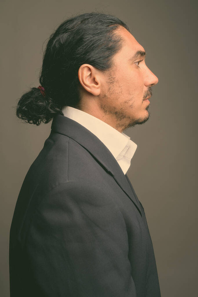Hombre de negocios guapo con bigote usando traje sobre fondo gris - Foto, Imagen