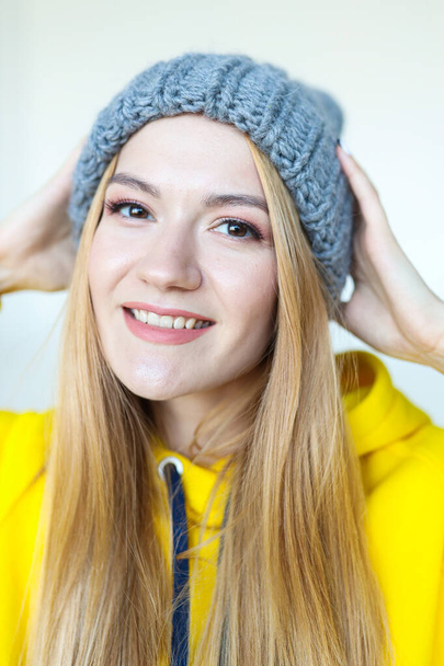 Portrait of a young woman in a winter hat and a bright yellow hoodie - Foto, imagen