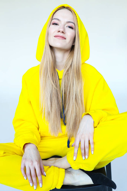 A young woman poses in a bright yellow tracksuit - Photo, Image