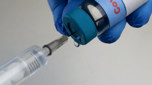 Védőkesztyűben dolgozó egészségügyi dolgozó kezei a Covid-19 koronavírus vakcinát új, eldobható fecskendőbe szívják üvegből készült injekciós üvegből. Globális járvány. Közelkép. - Felvétel, videó