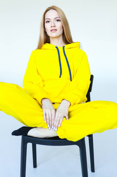 A young woman poses in a bright yellow tracksuit - Fotoğraf, Görsel