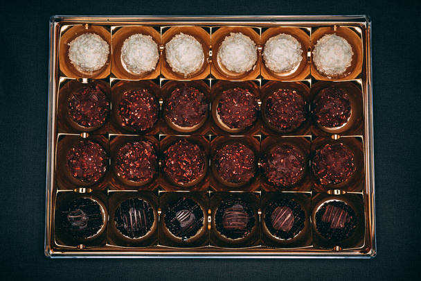 A chocolate box with dark and milk chocolate, and coconut ball sweets - Photo, image