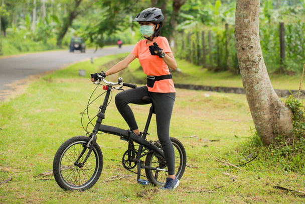 Kaunis aasialainen nainen pyöräilijä yllään kasvonaamio - Valokuva, kuva