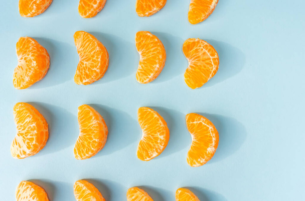 An overhead shot of small mandarin slices placed on a light blue background - Фото, зображення