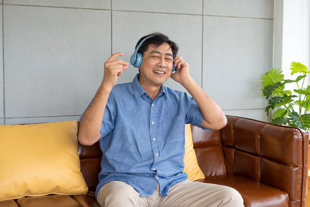 Starszy dziadek azjatycki cieszyć się i czuć szczęśliwy słuchając muzyki ze słuchawek bezprzewodowych, które strumieniowo muzyki ze smartfona lub tabletu. Emerytura w podeszłym wieku z dobrym zdrowiem. - Zdjęcie, obraz