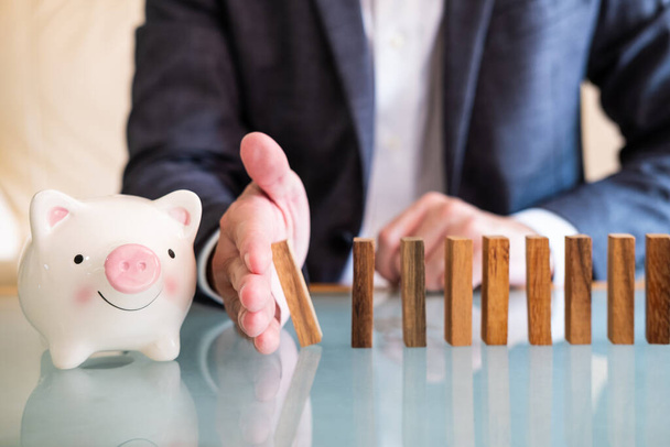 Selective focus at piggy bank. Agent business man with suit stop or prevent the wood brick to collapse and create damage on piggy bank. financial planning or insurance for wealth protection concept. - Photo, Image