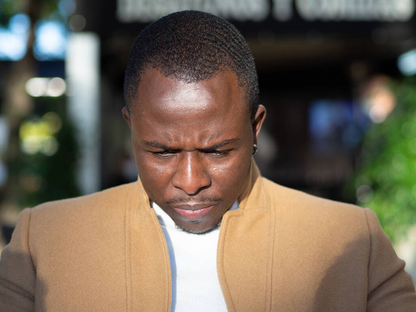 A shallow focus of an adult African male wearing a beige coat outdoors under the sunlight - Foto, Imagem
