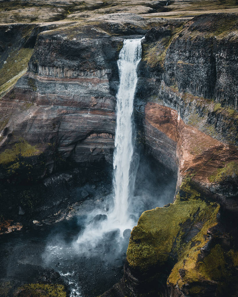 A vertical shot of a beautiful waterfall surrounded by rocky cliffs in Switzerland - Fotoğraf, Görsel