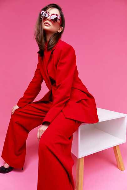 Fashion model in red suit and sunglasses. Studio shot. - Fotó, kép