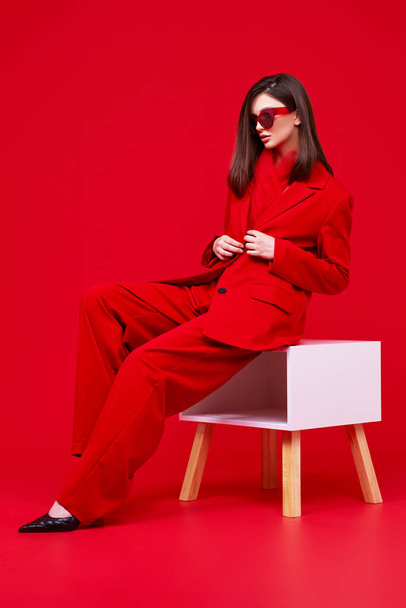 Fashion model in red suit and sunglasses. Studio shot. - Photo, image