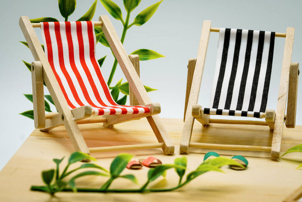 A closeup of small folding chair figures on a wooden table - concept of holidays and vacation - Foto, imagen