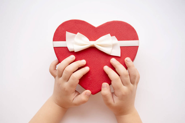 nyitott piros szív ajándék doboz fehér szalag fehér háttér babakéz - Fotó, kép