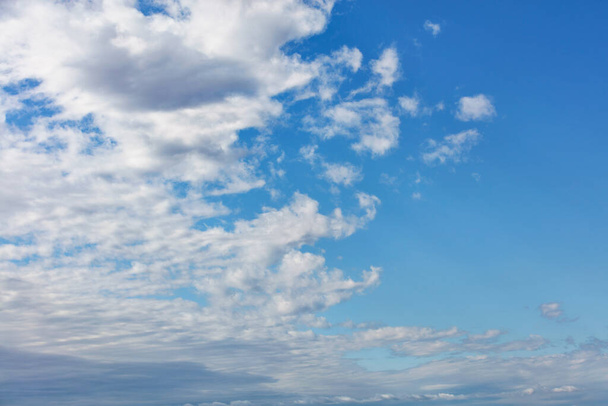 白いふわふわの雲が空に広がり、純粋な青を明らかにし、写真を半分に分割します。. - 写真・画像