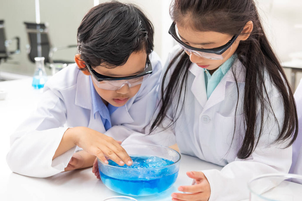 Mladý asijský chlapec a dívka student nosit ochranné Google při studiu a dělat vědecký experiment ve třídě s učitelem. Učím se a bavím se. Koncept učebny chemie nebo biologie.  - Fotografie, Obrázek