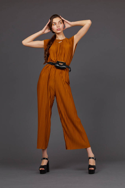 High fashion portrait of young elegant woman in brown overalls. Waist bag, grey color, studio shot - Foto, immagini