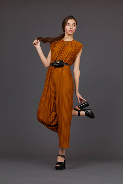 High fashion portrait of young elegant woman in brown overalls. Waist bag, grey color, studio shot - Photo, Image