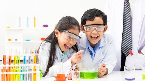 Молодой азиатский мальчик и девочка студент носить защитные Google во время учебы и сделать научный эксперимент в классе с учителем. Учиться и веселиться. Концепция кабинета химика или биологии.  - Фото, изображение