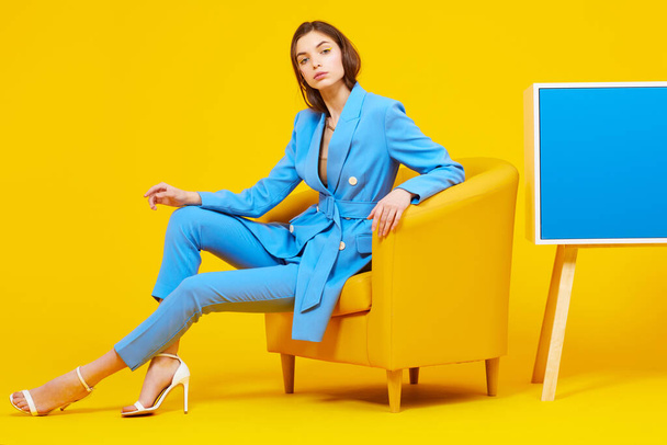 High fashion portrait of young elegant woman in blue suit. Yellow background, studio shot - Photo, image