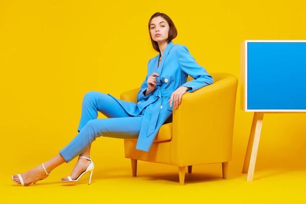 High fashion portrait of young elegant woman in blue suit. Yellow background, studio shot - Photo, Image