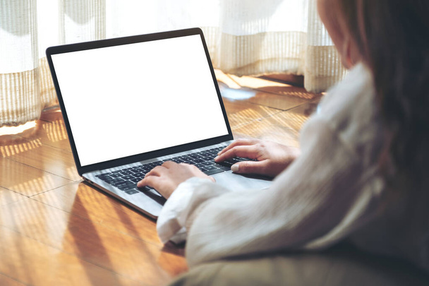 Mockup image of a woman typing on laptop computer with blank white desktop screen while laying down on the floor with feeling relaxed - Foto, imagen