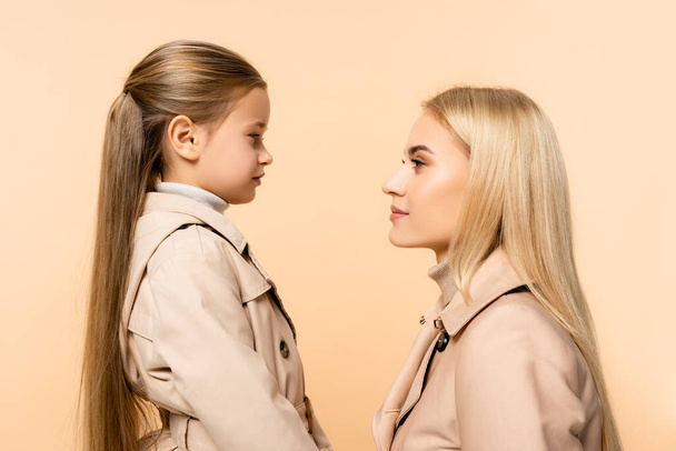side view of mother and daughter looking at each other isolated on beige - Foto, afbeelding