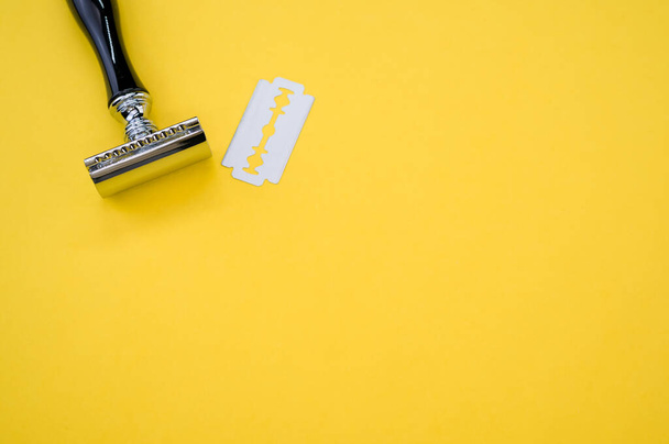 A top view of a mechanical razor and blade isolated on yellow background - Foto, afbeelding