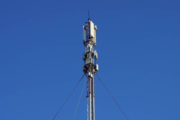 Hohe Eisenstange mit grauen Antennen auf der Straße vor blauem Himmel - Foto, Bild