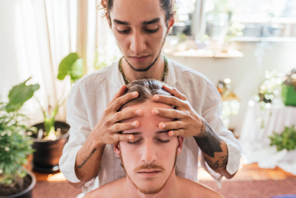 Zdjęcie człowieka korzystającego z masażu twarzy siedząc w ręczniku. - Zdjęcie, obraz