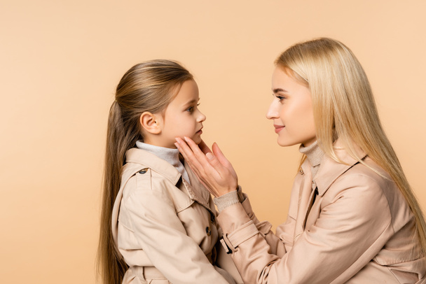 side view of caring mother touching face of daughter isolated on beige - Photo, Image