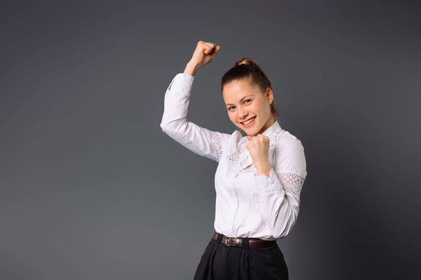 Young girl entrepreneur won the project. Rejoices at success on a gray background. - Fotoğraf, Görsel