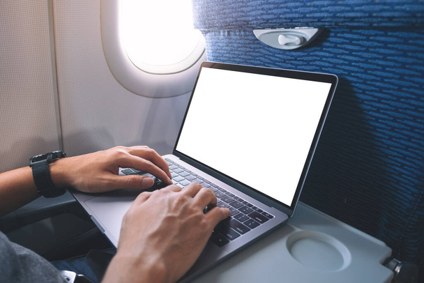 Mockup image of a man using and typing at laptop computer with blank white desktop screen while sitting in the cabin - Fotografie, Obrázek