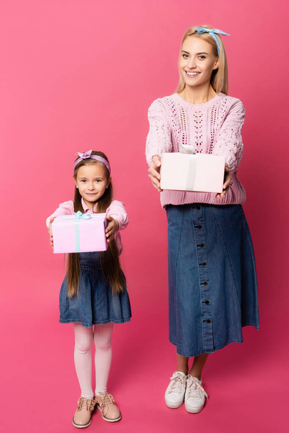 happy mother and daughter holding presents on pink - Fotografie, Obrázek