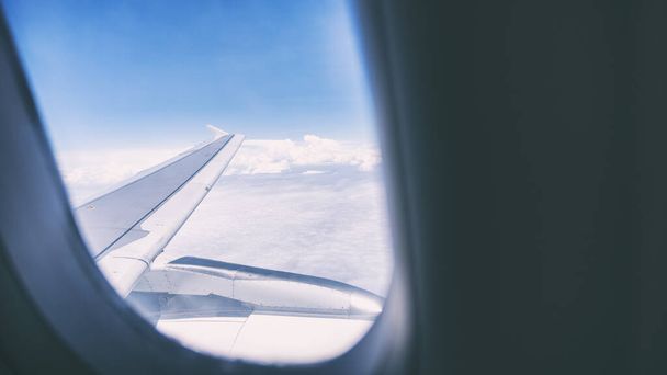 Крыло самолета и голубое небо в облачный день через окно - Фото, изображение