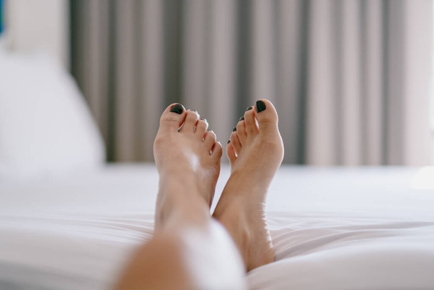 Closeup image of a woman's feet on a white bed - Фото, зображення