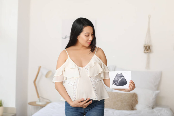 Terhes ázsiai nő ultrahang kép otthon - Fotó, kép