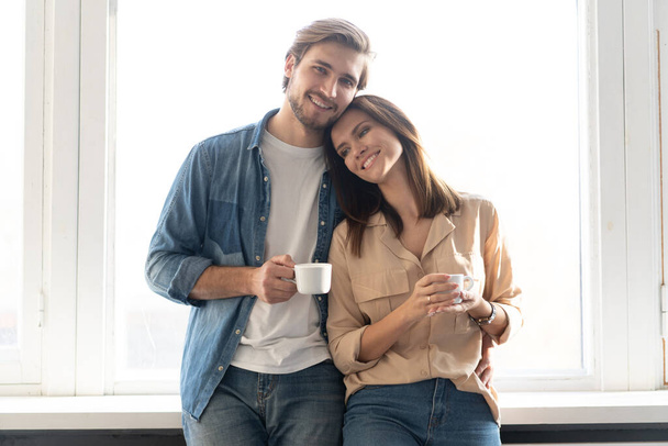 Portrait of a couple drinking coffee in their living room - Фото, изображение