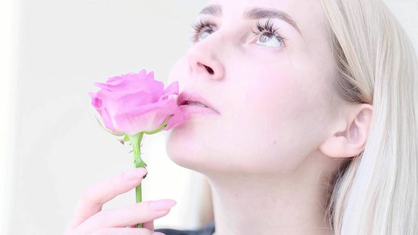 Gyönyörű fiatal nő, finom rózsa virággal. A lány tiszta, friss bőre megérinti az arcát virágokkal. lágy fókusz, szelektív fókusz - Fotó, kép