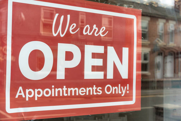 Outdoor sign showing pandemic services during virus. Text on vintage red sign 'We are OPEN Appointments Only!' A business sign stating OPEN hanging door at the hairdresser or beautician. Hair dresser. - Photo, Image