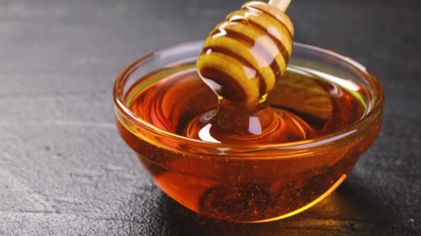 Honing in glazen pot met honingdipper over zwarte achtergrond - Video