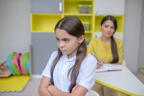 Upset girl with folded arms and psychologist - Foto, Imagen