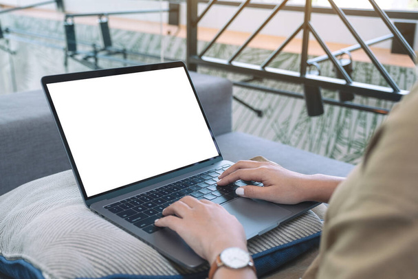 Imagen burlona de una mujer usando y escribiendo en el teclado del ordenador portátil con pantalla blanca en blanco mientras está sentado en la sala de estar - Foto, Imagen