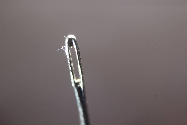 Macro fotografía de aguja de coser. Aguja pequeña con ojal vacío, aislada sobre el fondo negro. - Foto, Imagen