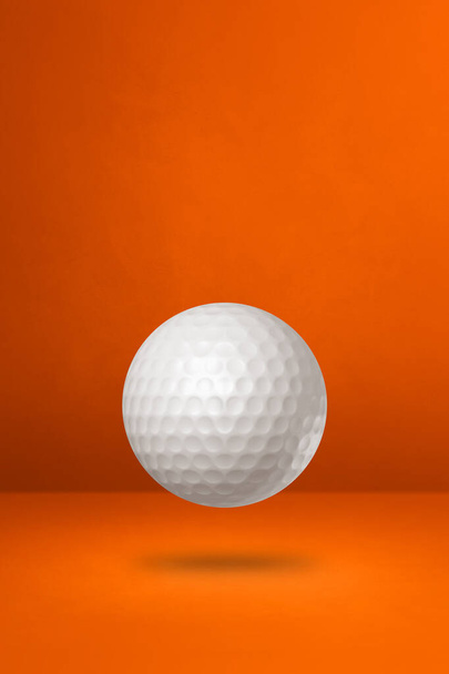 White golf ball isolated on a orange studio background. 3D illustration - Foto, Imagen