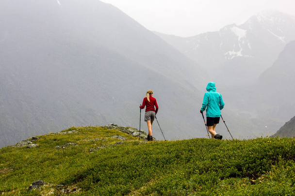 Δύο γυναίκες πεζοπόροι περνούν από ορεινό μονοπάτι σε βροχερό καιρό - Φωτογραφία, εικόνα