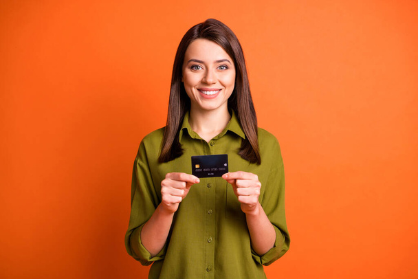 Photo of cheerful positive girl hold credit card toothy smile wear green shirt isolated orange color background - Φωτογραφία, εικόνα