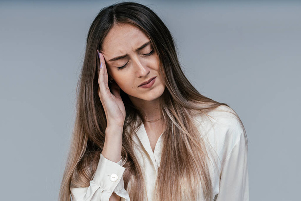 Traurig müde junge Frau berührt ihre Stirn mit Kopfschmerzen, Migräne oder Depressionen, frustriertes Mädchen sorgt sich um Probleme, fühlt sich gestresst. - Foto, Bild